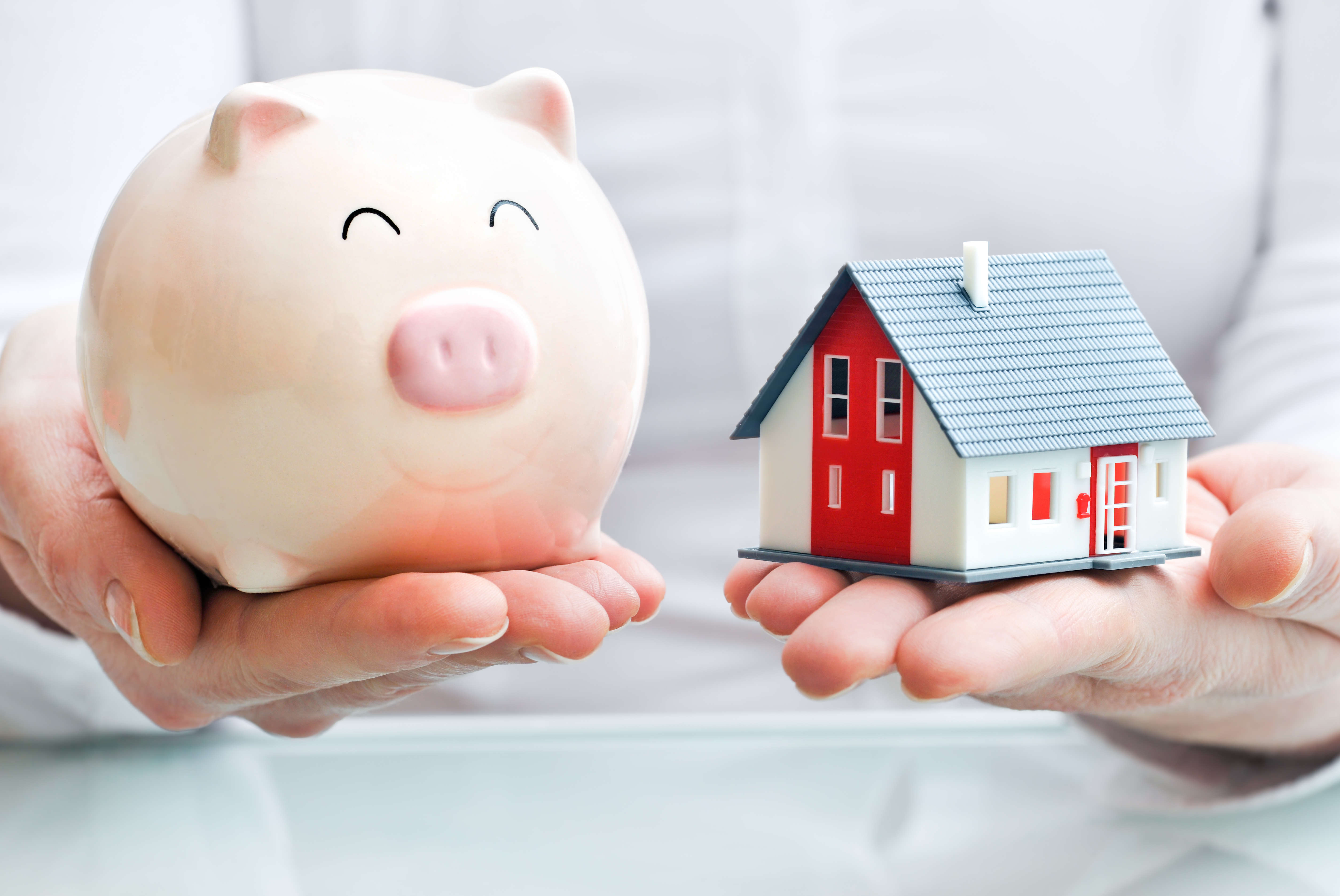 Hands holding a piggy bank and a house model. Housing industry mortgage plan and residential tax saving strategy