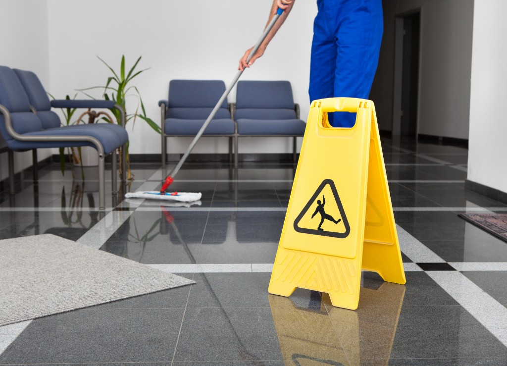 Working janitor with slippery sign