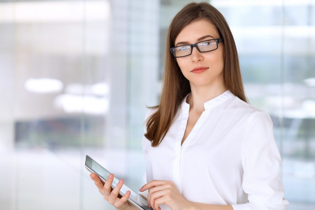 woman wearing glasses holding an ipad